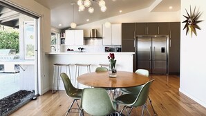 Una cucina moderna con isola centrale, elettrodomestici in acciaio inossidabile e zona pranzo con tavolo rotondo e sedie verdi.