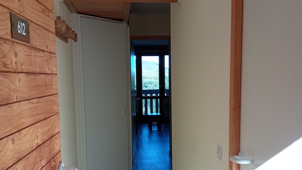 A hallway with wooden walls, a door labeled '612', and a view of a balcony with a railing. - MOUNTAIN-STYLE APARTMENT AT THE FOOT OF THE SLOPES SLEEPS 5 (La plagne - Belle-plagne)