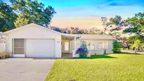 A single-story house with a garage and a front yard. - Boutique Stay: Near Beach,  PSP4, Billiard or PingPong, Fire Pit, Private Yard (New Port Richey)