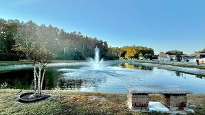 A tranquil outdoor setting with a fountain, a small stone structure, and a tree in the foreground. - Boutique Stay: Near Beach,  PSP4, Billiard or PingPong, Fire Pit, Private Yard (New Port Richey)