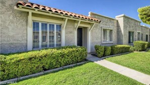 A two-story house with a stucco exterior, a tiled roof, and a number '5105' on the front.