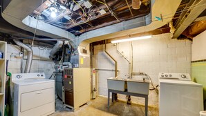 Een wasserette met twee wasmachines, een gootsteen en zichtbare leidingen.