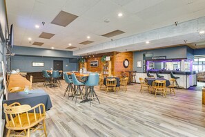 Enjoy dining in the restaurant with a variety of seating options and a prominent wooden wall featuring a clock.