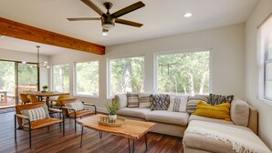 Un salon spacieux doté d’un plancher en bois, d’un ensemble de canapés, d’une table basse et d’un ventilateur de plafond.