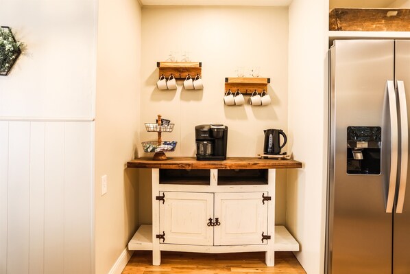 A kitchen with a wooden countertop, a stainless steel refrigerator, and two wall-mounted shelves holding mugs. - Medical District Retreat 4 Bedroom Walk to Tech (Lubbock)