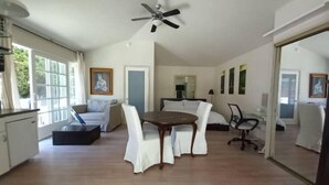A spacious living area with a dining table, sofas, and a ceiling fan.