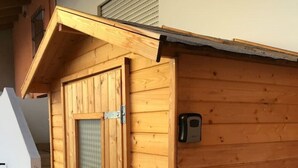 Una estructura de madera con una puerta, un ventanal pequeño, un picaporte metálico y un respiradero en la pared.