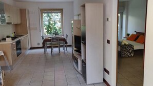 Una cocina moderna con comedor, televisor integrado y una habitación visible a través de una puerta abierta.