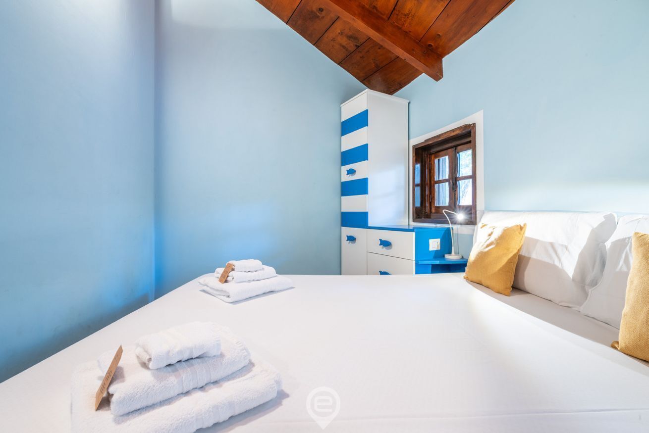 A bedroom with a bed, a nightstand, a wardrobe, and a window.