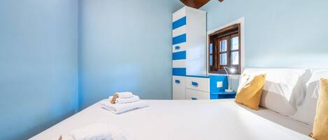 A bedroom with a bed, a nightstand, a wardrobe, and a window.