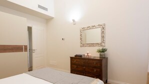 A bedroom with a bed, a dresser, a mirror, and a door. - Apartments Florence - Buontalenti Exclusive (Firenze)