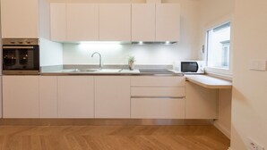 A modern kitchen with white cabinets, a stainless steel sink, a microwave, and a built-in oven. - Apartments Florence - Buontalenti Exclusive (Firenze)