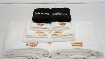 A neatly folded white towel with a PMI logo and the word "Makeup" on a black towel placed on top.