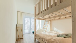 Quarto com beliche, escada de madeira, espelho e janela com cortinas.