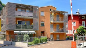 A multi-story building with balconies, a gated entrance, and a clear sky.