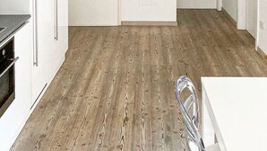 A room with a wooden floor, white walls, a white cabinet, and a white table.