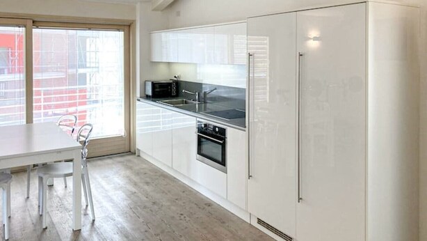 A modern kitchen with white cabinetry, a built-in oven, and a microwave.