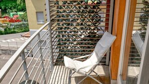 A balcony with a white chair, metal railing, and tiled floor.