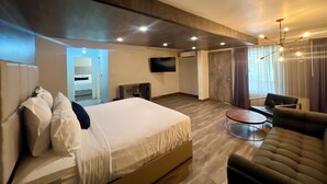 A modern hotel room with a large bed, a sofa, a TV, and a dining area. - Hotel Sunio City (Tijuana)