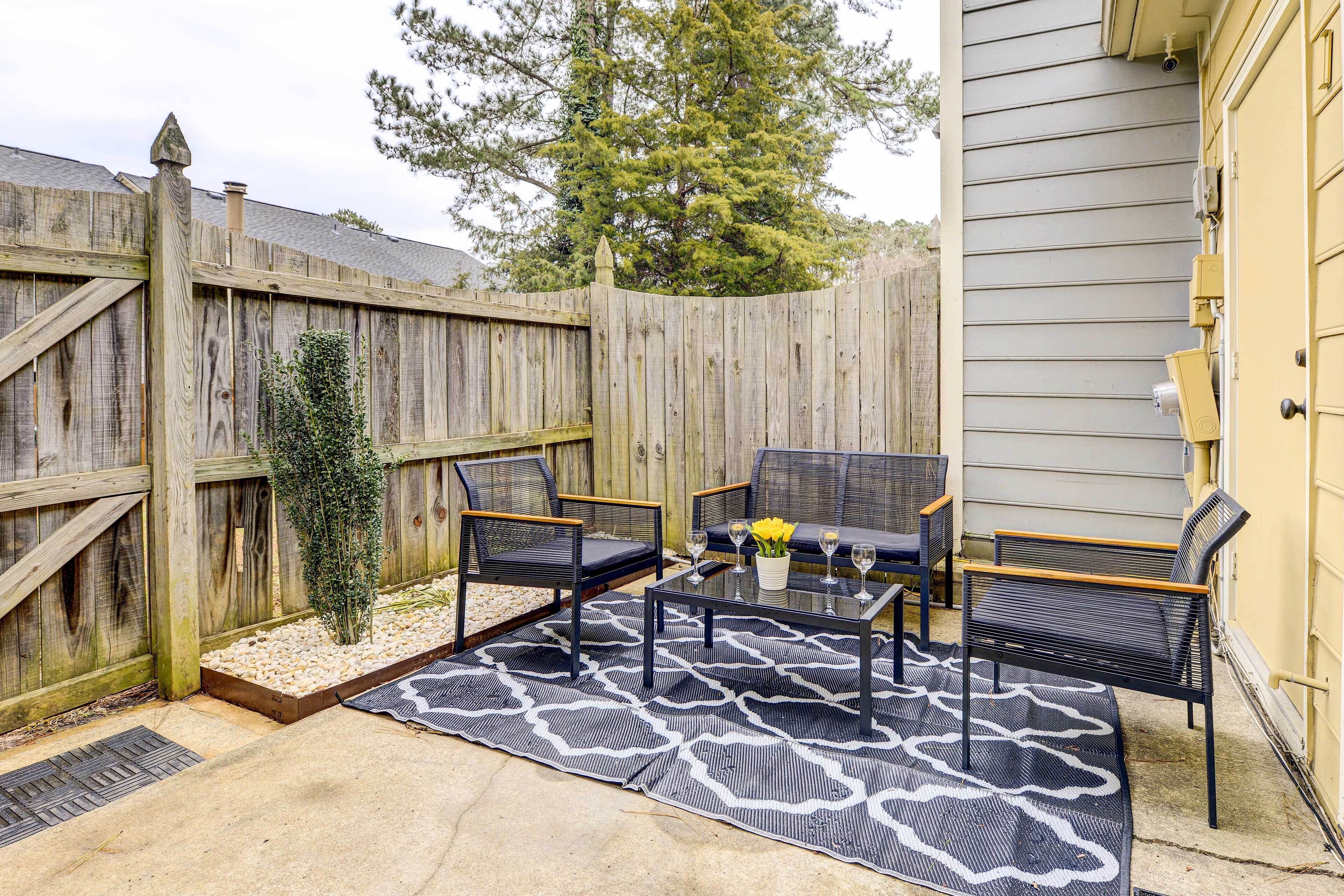Une terrasse avec une clôture en bois, des meubles d’extérieur et une plante en pot.