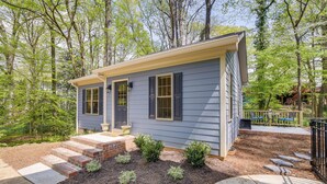 A single-story house with a front porch, steps leading to the door, and a small garden area with shrubs and stepping stones. - Beautiful Raleigh Cottage Rental: 5 Mi to Downtown (Raleigh)