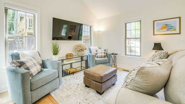 A living room with a sofa, ottoman, and armchair, a coffee table, and a TV. - Beautiful Raleigh Cottage Rental: 5 Mi to Downtown (Raleigh)