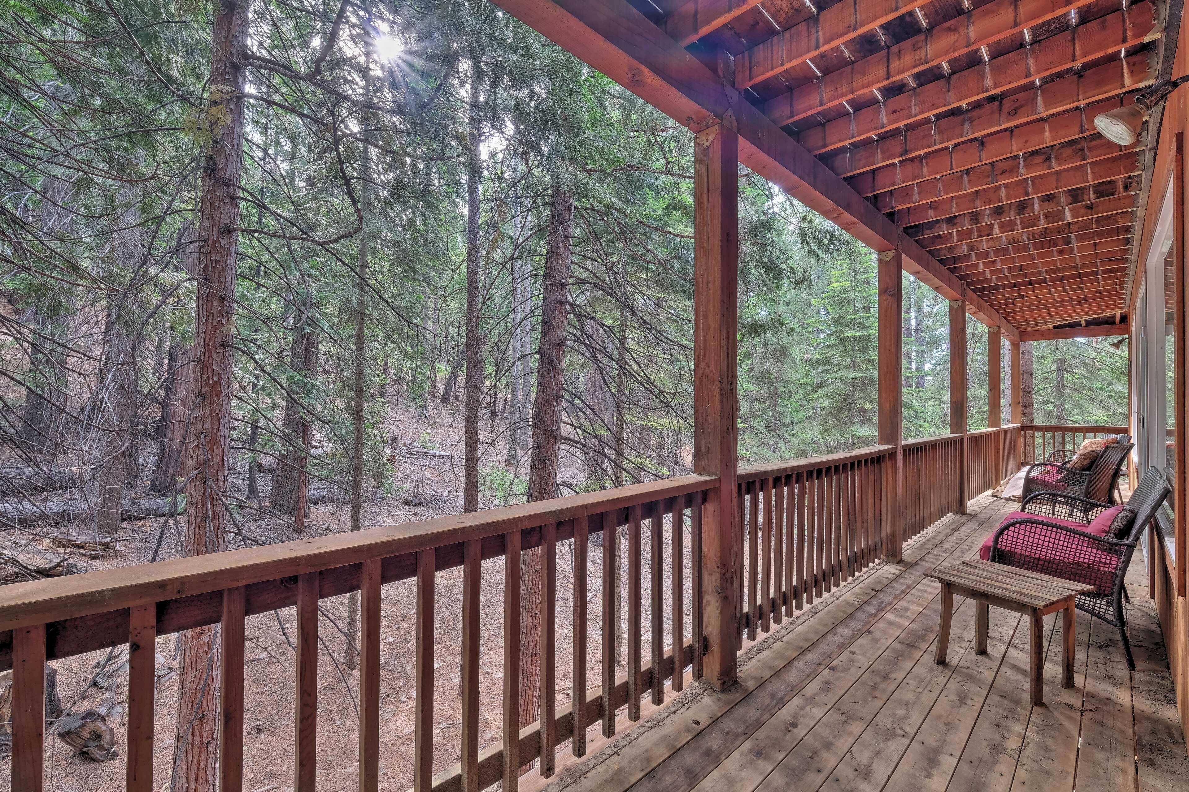 A wooden deck with a railing, a table, and two chairs.