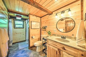 A wooden cabin bathroom with a toilet, sink, and mirror. - Rustic-chic Woodland Hideaway w/ Hot Tub! (Sandpoint)