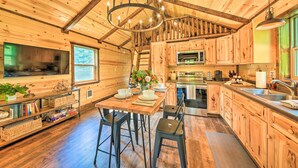 A rustic wooden interior with a dining area, kitchen, and large windows. - Rustic-chic Woodland Hideaway w/ Hot Tub! (Sandpoint)