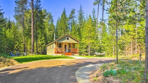 A cabin with a porch, surrounded by a forest. - Rustic-chic Woodland Hideaway w/ Hot Tub! (Sandpoint)