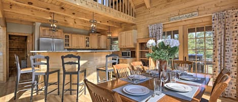 A spacious wooden cabin with a dining area, kitchen, and a balcony.