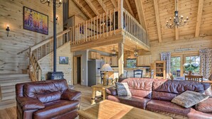 A spacious living area with a wooden staircase, leather sofas, and a dining area with a view of the outdoors. - Lazy Beaver Lodge Pagosa Cabin w/ Deck, Fire Pit (Pagosa Springs)