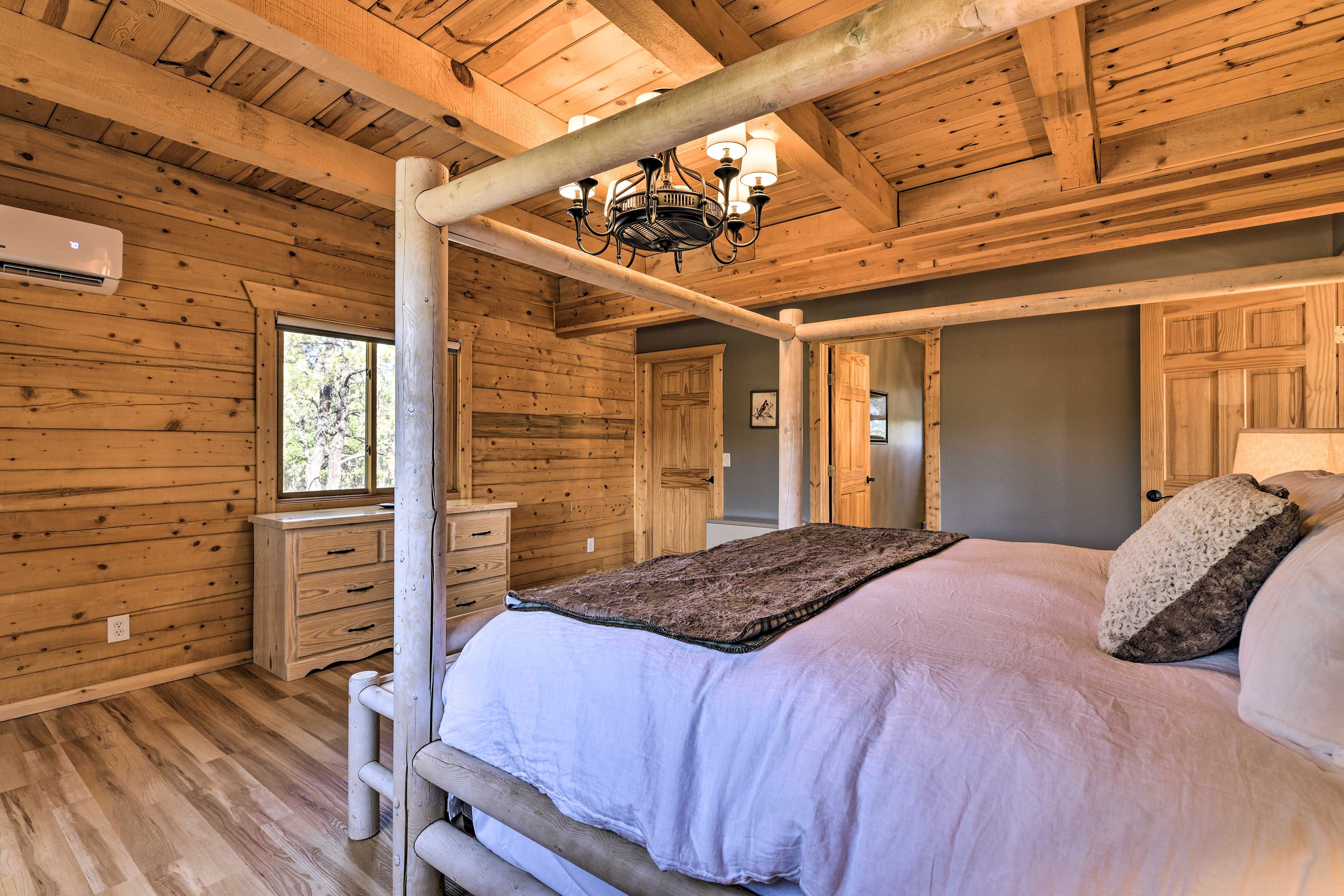 A log cabin bedroom with a four-poster bed, wooden walls, and a chandelier.
