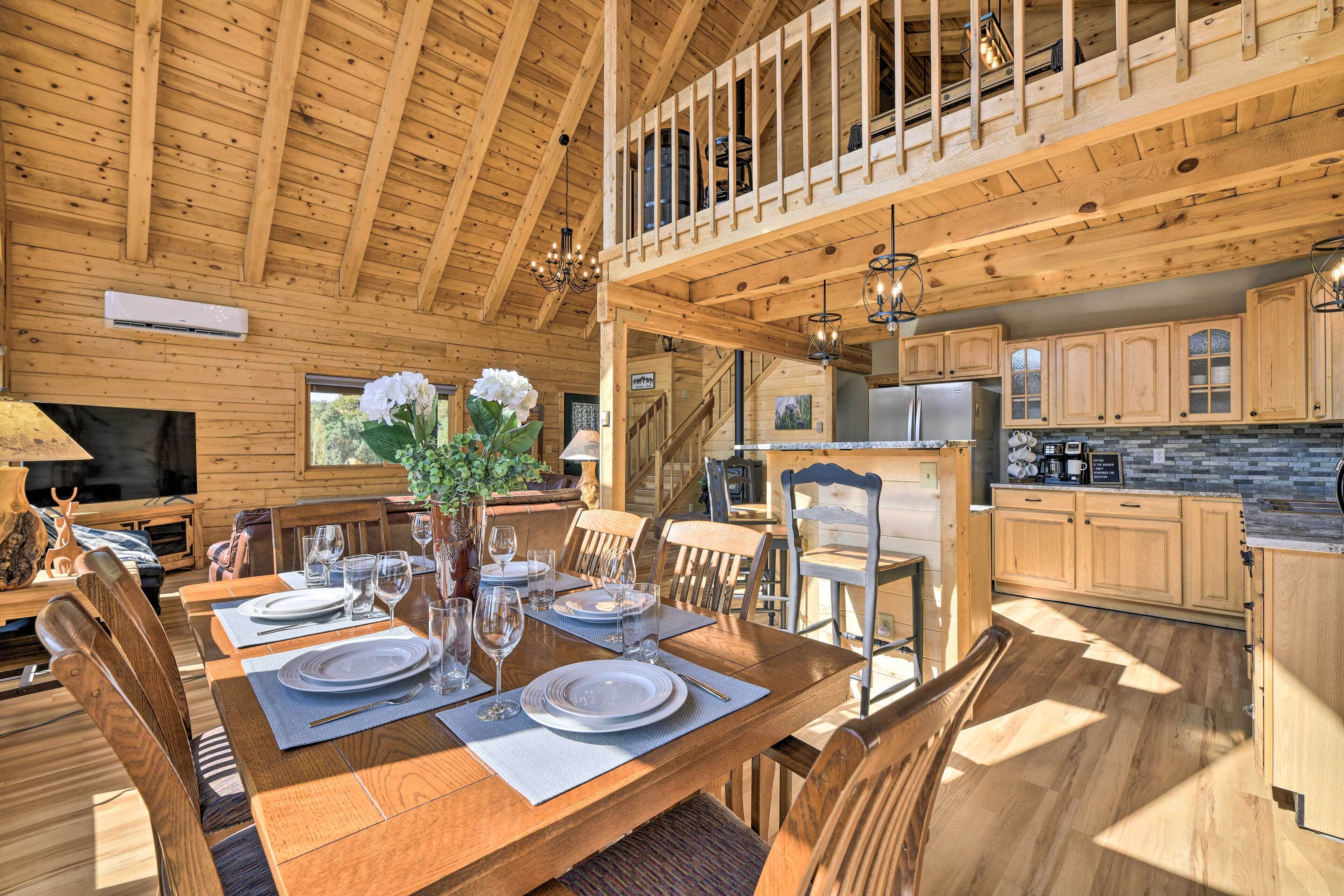 A wooden cabin with a dining area set for four, a kitchen with granite countertops, and a loft bedroom with a balcony.