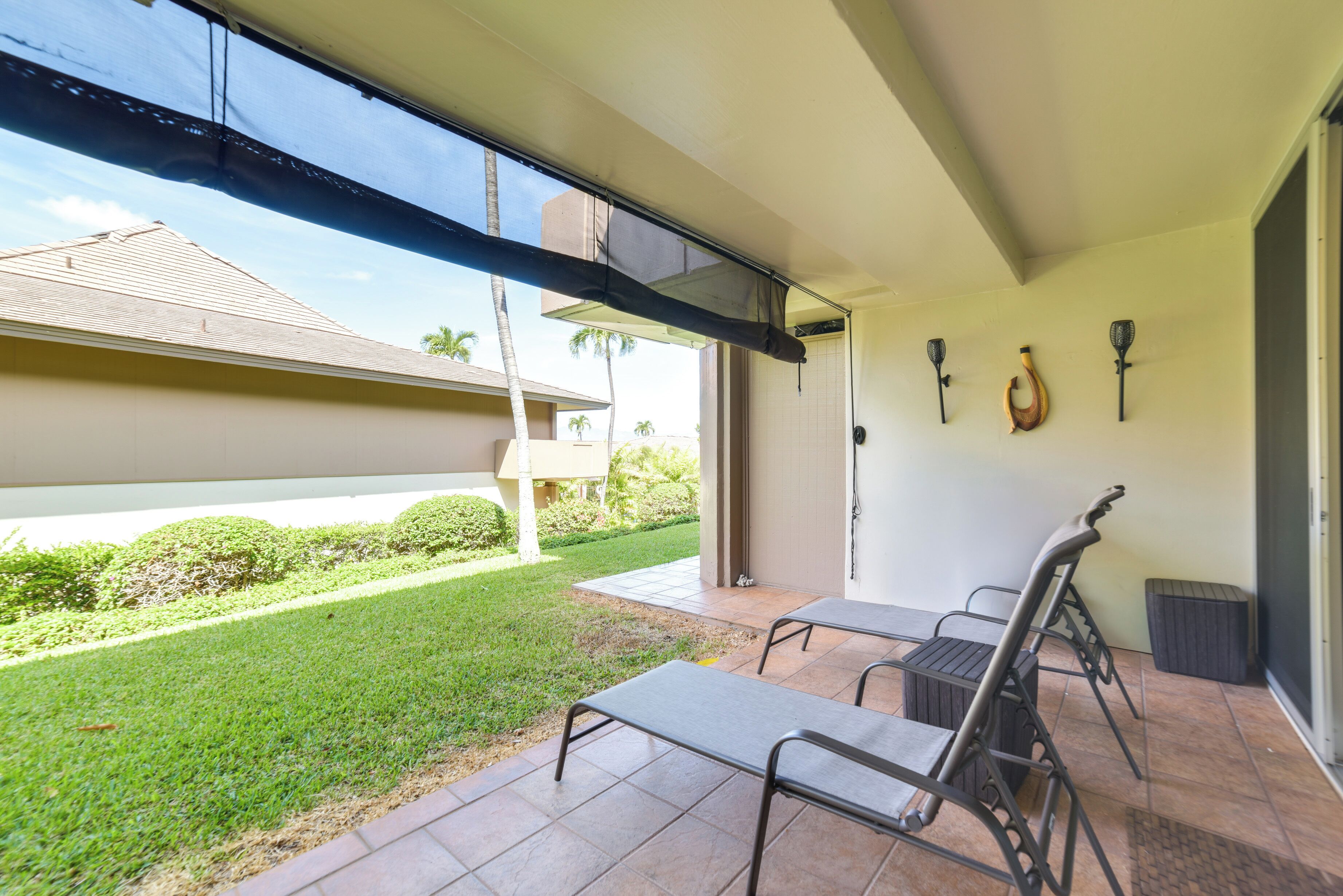 A covered patio area with a table and chairs, a door leading outside, and a wall-mounted light fixture.