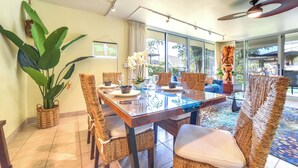 A dining area with a glass table, wicker chairs, and a large plant. - Island Oasis Near Kaanapali Beach & Black Rock (Kaanapali)