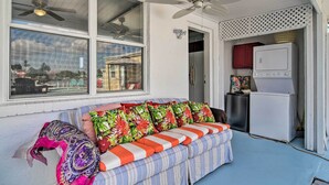 A room with a sofa, ceiling fans, a refrigerator, and a window with a view of buildings. - Bayside Pad w/ Pool Access & Dock: 1/2 Mi to Beach (Indian Rocks Beach)