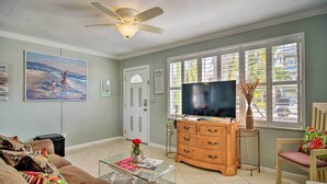 A living room with a ceiling fan, a television, a wooden dresser, and a window with blinds. - Bayside Pad w/ Pool Access & Dock: 1/2 Mi to Beach (Indian Rocks Beach)