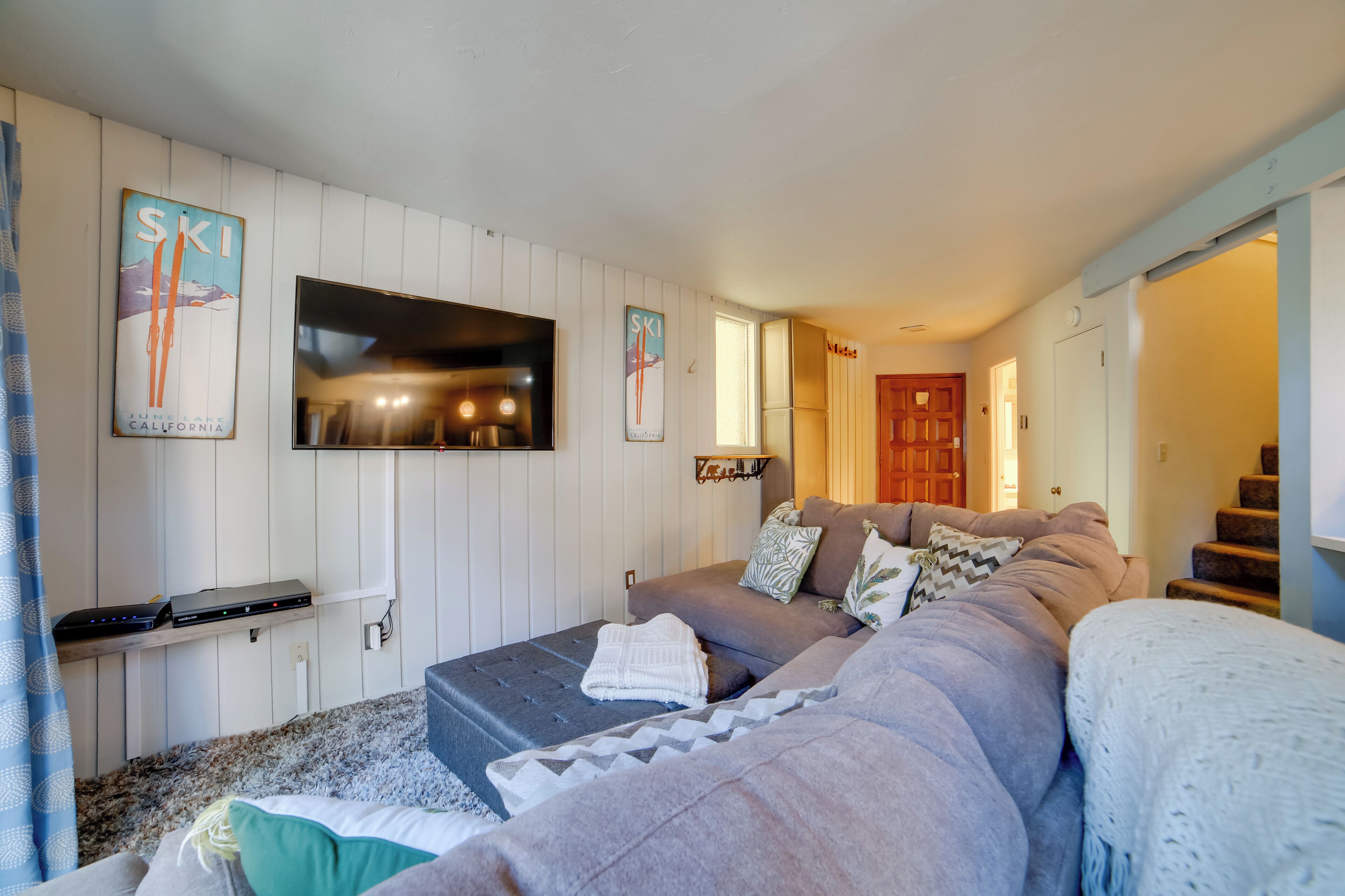 A bedroom with a bed, a TV mounted on the wall, and a door leading to another room.