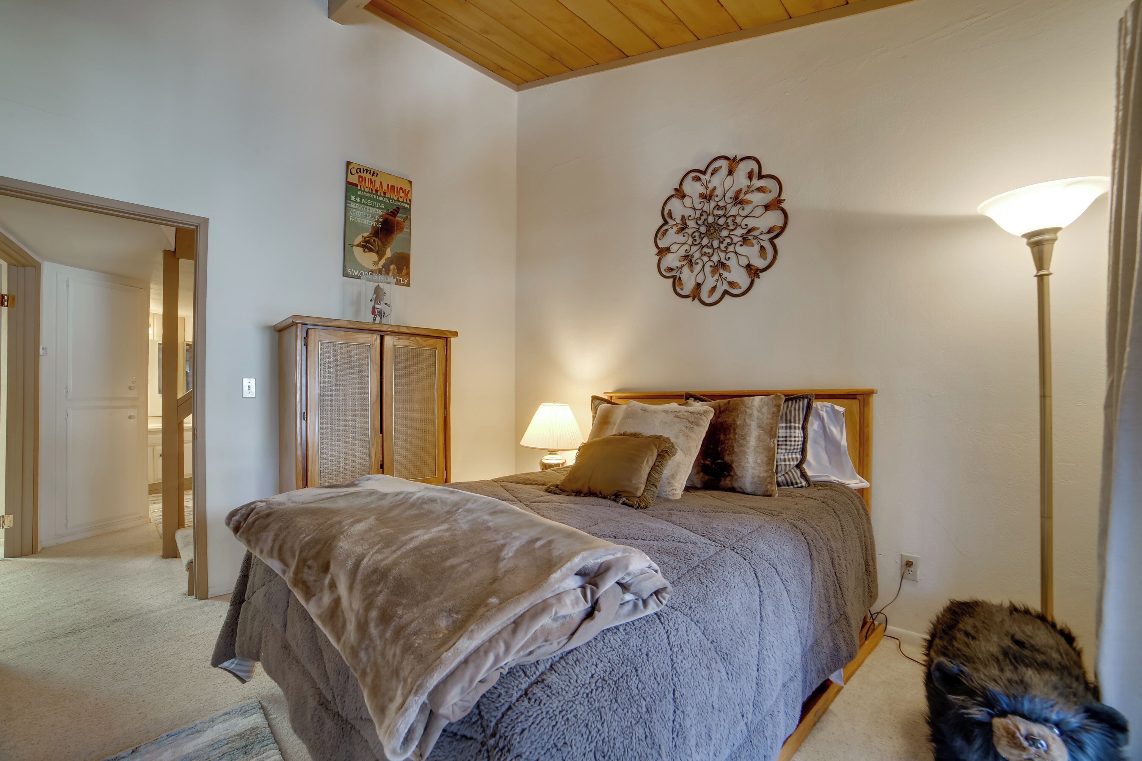 A bedroom with a bed, a lamp, a decorative wall piece, and a poster.