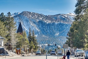 A street view with a mountain backdrop, traffic lights, and a sign for Mammoth Mountain Supply.