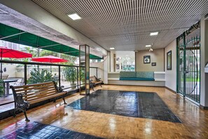 A spacious indoor area with a wooden bench, a black mat, and red umbrellas. - Waikiki Condo: Walk to Beach, Shops & Restaurants (Honolulu)