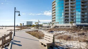 A wooden boardwalk leading to a modern building with balconies.