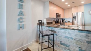 A modern kitchen with a bar area, a microwave, and a refrigerator.