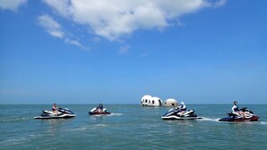 Vier Jetskis auf dem Wasser, bewölkter Himmel und drei runde Bauwerke im Hintergrund.