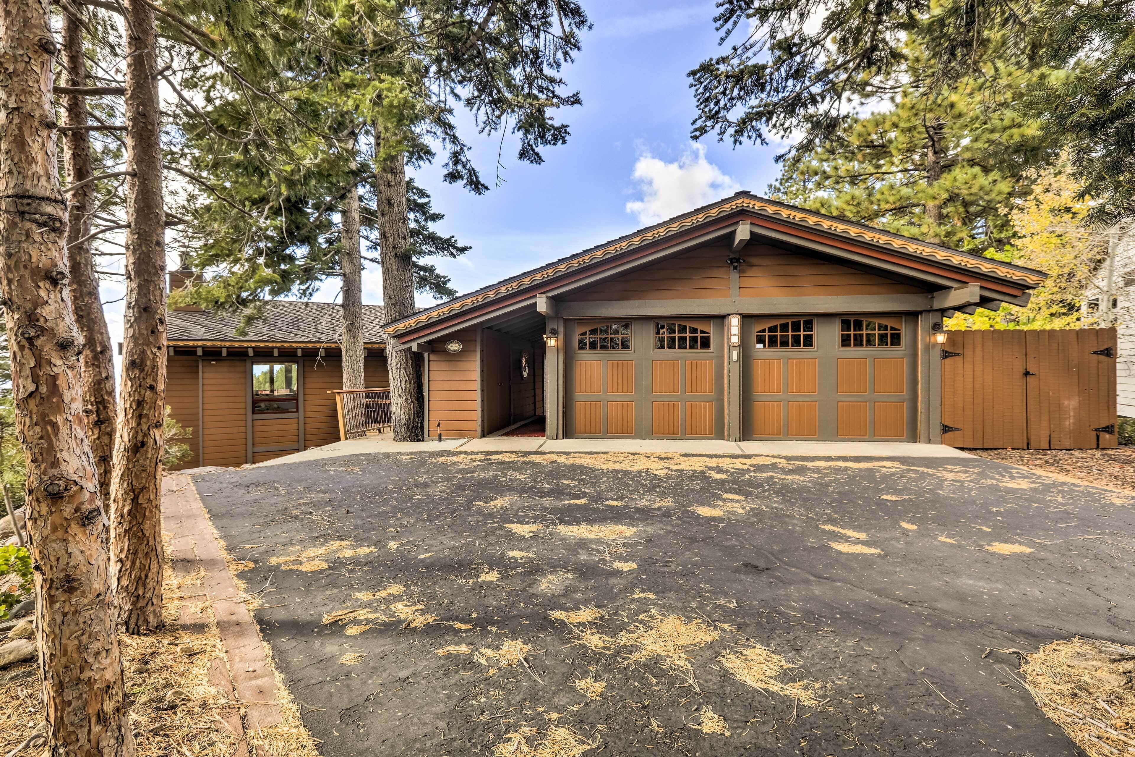 A two-story house with a garage, surrounded by tall trees and a well-maintained driveway.