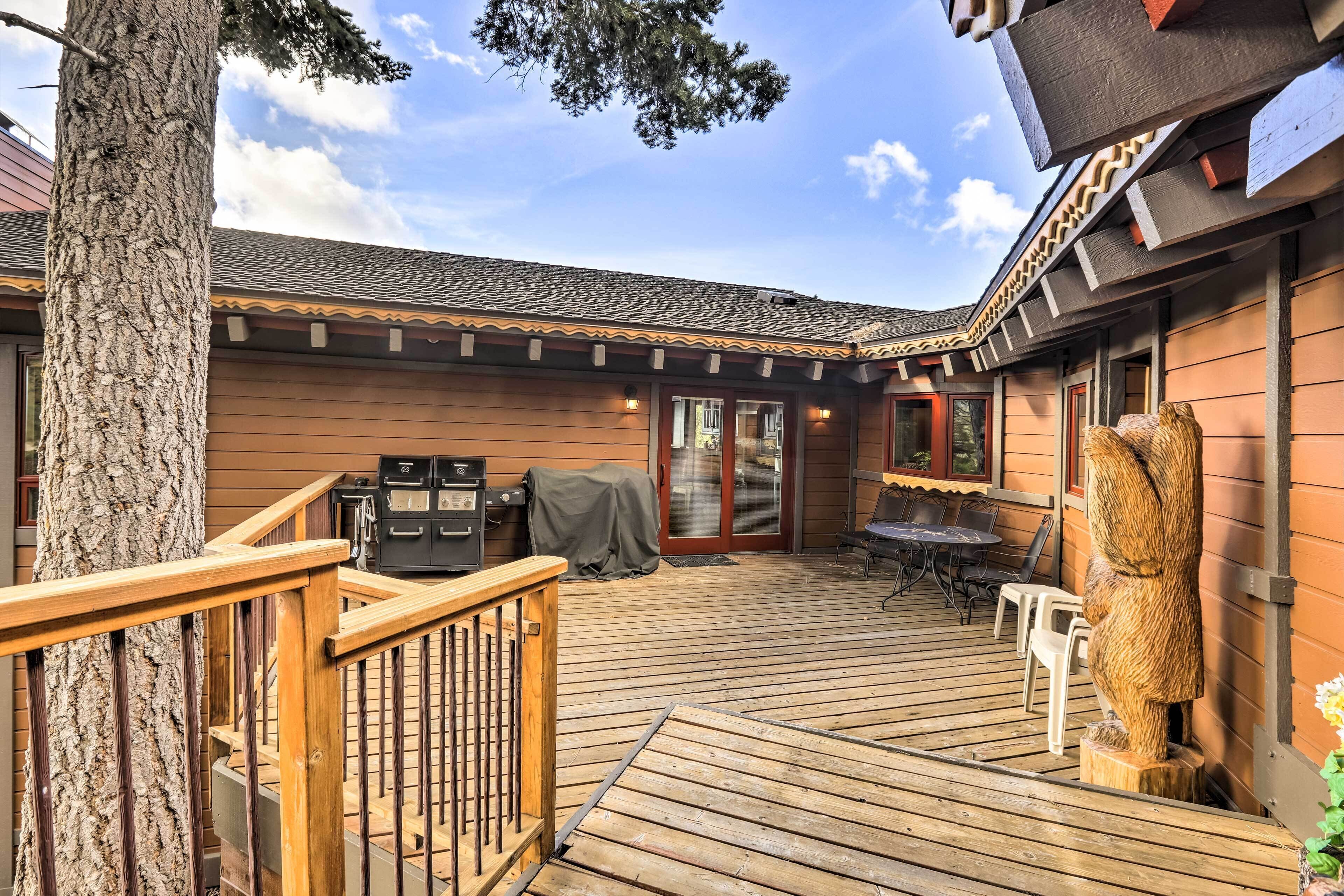 A wooden deck with a railing, a covered grill, and a stone sculpture.