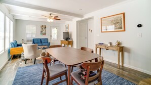 A dining area with a wooden table, four chairs, a blue rug, and a ceiling fan. - Charleston Home w/ Porch - 3 Mi to Folly Beach! (Charleston)
