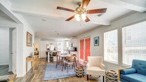 A spacious living area with a ceiling fan, a dining table with chairs, a sofa, and a kitchen in the background. - Charleston Home w/ Porch - 3 Mi to Folly Beach! (Charleston)