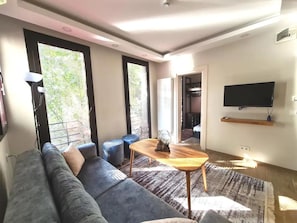 A modern living room with a grey sofa, a wooden coffee table, and a TV mounted on the wall. - Galata Nazapart (Istanbul)